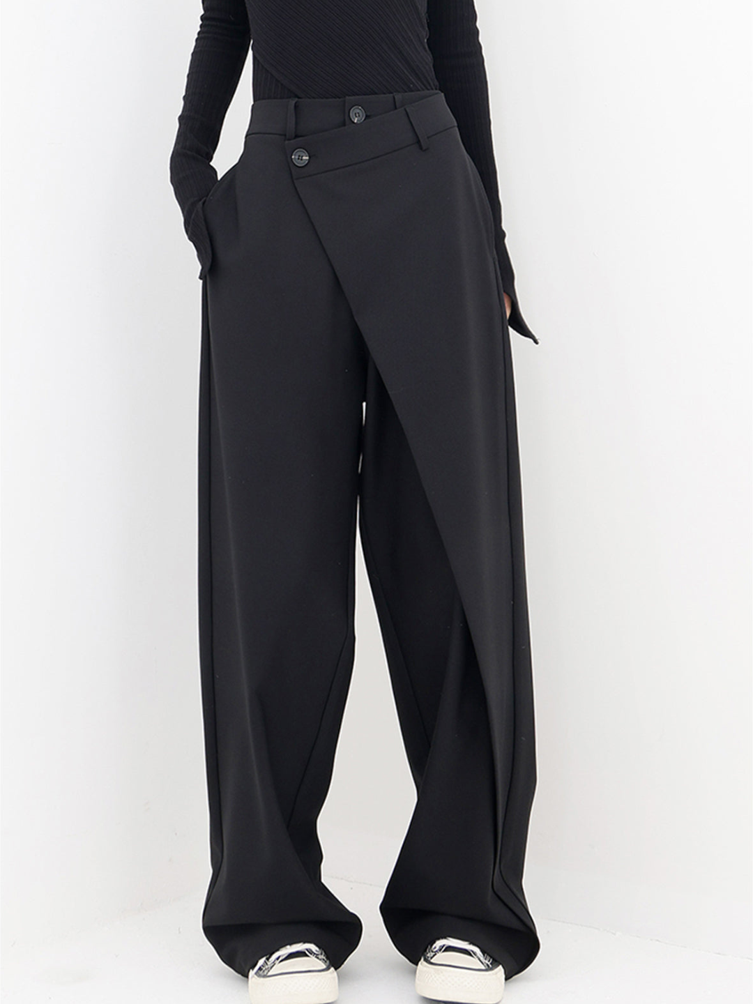 Zwarte asymmetrische baggy damesbroek met hoge taille en unieke snit, voorkantweergave."